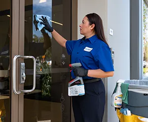 woman cleaning window, janitorial services