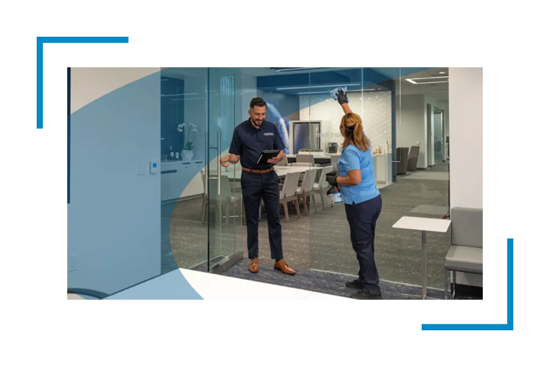 man and woman cleaning glass door in bank